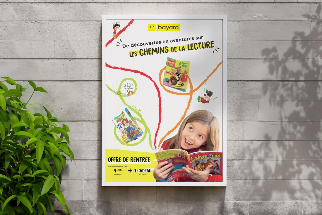 L’affiche Bayard « Les chemins de la lecture » encadrée sur un mur de briques, offre de rentrée en bas.