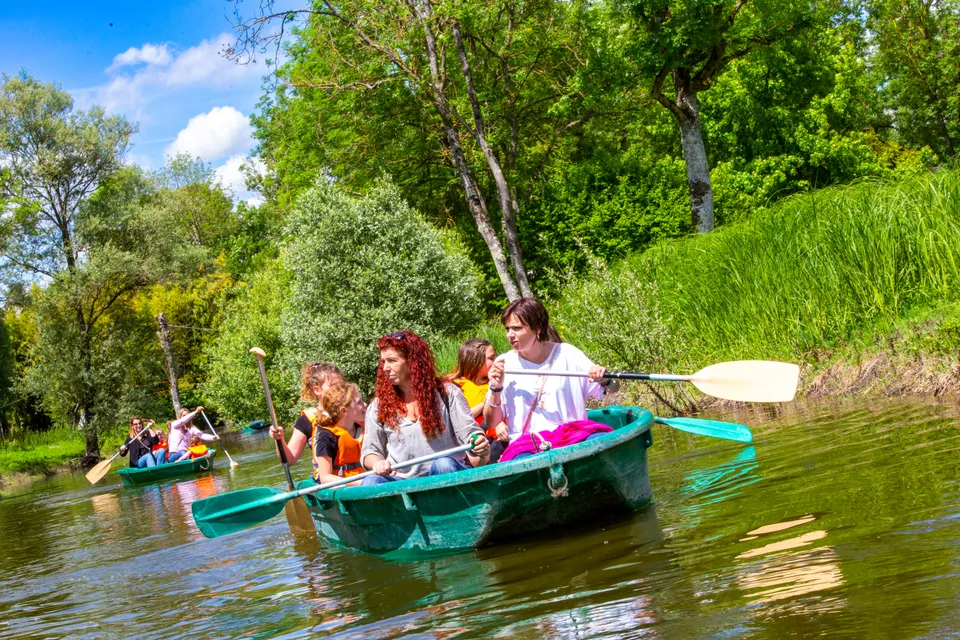 Des familles se promènent en barque sur l'eau, entourées de verdure, à Grinyland.