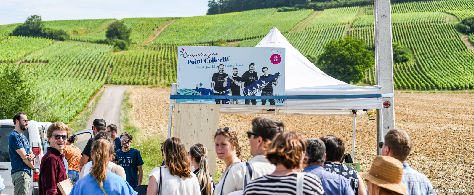 Des visiteurs rassemblés devant un « Point collectif » de La Route du Champagne en Fête, au milieu des vignes.
