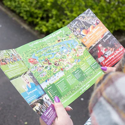 Le plan dépliant du parc Grinyland, ouvert et tenu à deux mains.