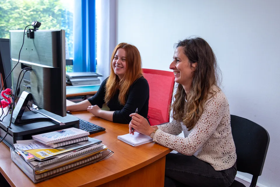 Deux collaboratrices de Fame échangent en souriant autour d'un bureau.