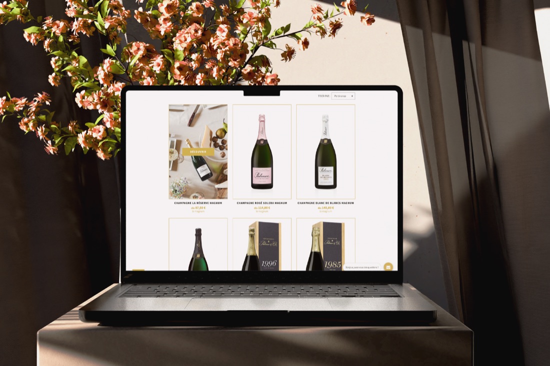 La page listant les cuvées Palmer & Co sur un ordinateur portable, devant un cerisier en fleurs.