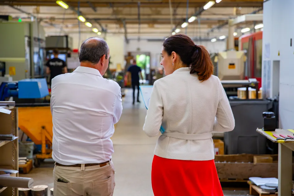Deux visiteurs parcourent l'allée centrale de l'atelier de Degoisey.