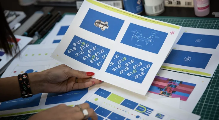 Un catalogue imprimé feuilleté à la main dans les bureaux de l'agence.